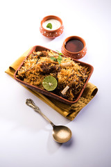 Gosht or Lamb Biryani prepared in Basmati Rice served with Yogurt dip in terracotta bowl. Selective focus