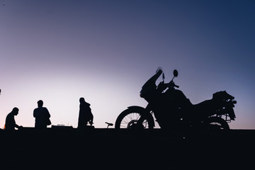 silhouette adventurous motorcycle on blue sunset sky with people, motorcyclists, motorcycle touring background, adventure and travel concept, active lifestyle