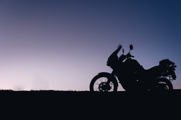 Obraz na płótnie Canvas silhouette adventurous motorcycle on blue sunset sky, motorcycle touring background, adventure and travel concept, active lifestyle