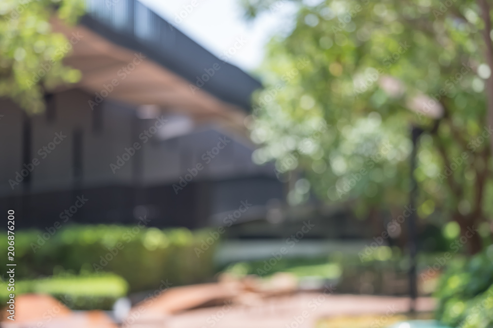 Aufkleber blurred abstract background of bench under tree in green at modern eco office building in sunny day.