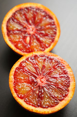 Two halfs of  raw red orange on black background 