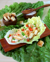 Salad with turkey, baked pepper, croutons and white sauce served in a salad leaf