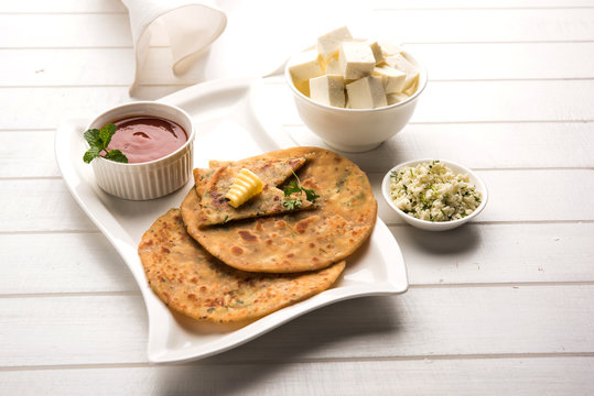 Stuffed Paneer Paratha with melting butter, served with fresh Cottage Cheese cubes and tomato ketchup. Selective focus