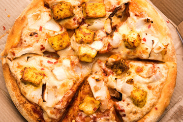 Paneer Pizza is an indian version of Italian dish topped with Cottage Cheese, served in a plate with white sauce. selective focus