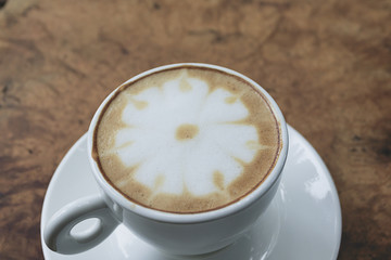 A cup of latte art on wood table in morning, Coffee with a pattern of milk in white cup.