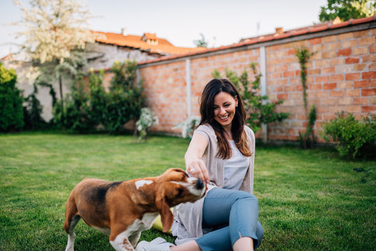 Young woman enjoy spending time with her dog in the backyard.