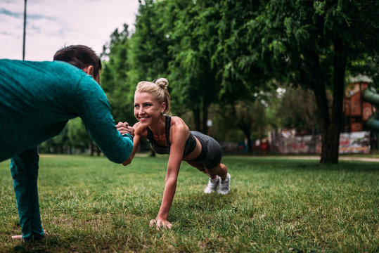 Couple doing push-ups outdoors.