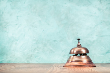 Retro hotel reception service desk bell front textured aquamarine concrete wall background. Vintage...