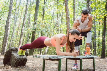 Beautiful woman doing a plank with man watching and cheering
