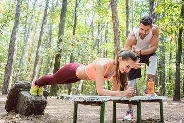  Beautiful woman doing a plank with man watching and cheering © Kzenon