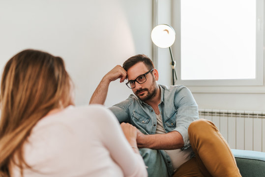 Two people talking while sitting on sofa.