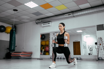Young beautiful woman working out with dumbbells in the gym.