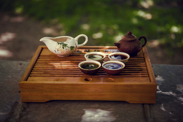 Teapot, bowl and four cups. Drinking Puer tea in nature.