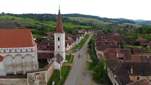 Group of friends on bicycles, riding through the village of Saschiz, close to the church tower on a country road. Cyclists on bikes outdoors, aerial view. Group of sporty friends riding a bikes 