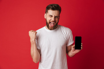 Excited young man showing display of mobile phone make winner gesture.