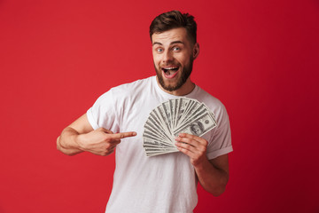 Excited young man holding money pointing.