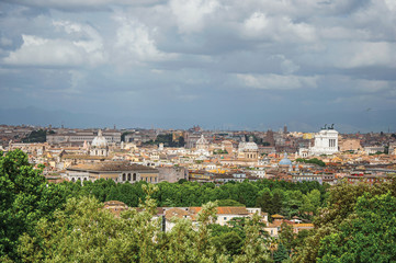 Fototapeta na wymiar Overview of trees, cathedrals domes, monuments and roofs on a cloudy day at Rome, the incredible city of the Ancient Era, known as 