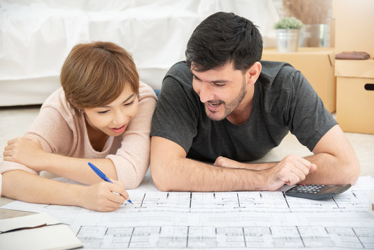 Happy young couple with blueprints planning their new house.