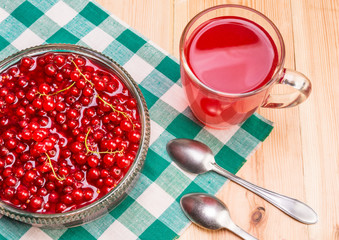 Homemade jam of red currant with a glass of juice, on a wooden table, top view.