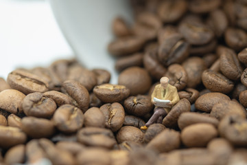 Relax, hobby and business concept. Businessman miniature figure sitting and reading a book on coffee bean with white cup of coffee