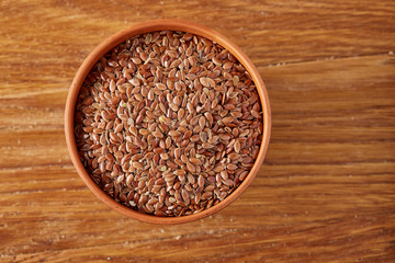 Top view on flax seeds in wooden bowl on rustic wooden background, selective focus.