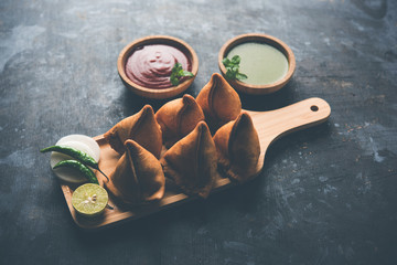 Samosa snack served with tomato ketchup and mint chutney