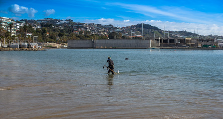 A man in a diving suit looking for coins metal detector at the bottom of the bay