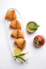 Samosa snack served with tomato ketchup and mint chutney
