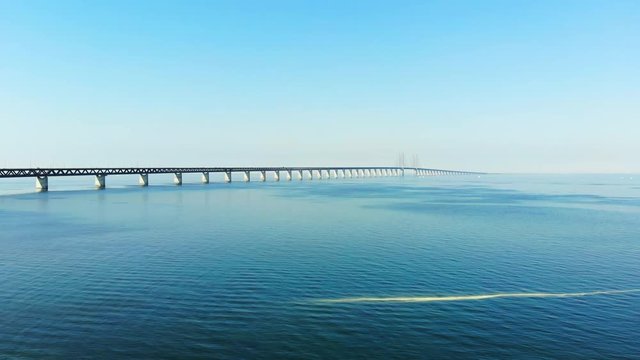 Aerial view of modern Oresund Bridge between Denmark and Sweden (Copenhagen and Malmo), clear blue sky, seascape of Baltic Sea with diagonal composition of very long sea bridge disappearing on horizon