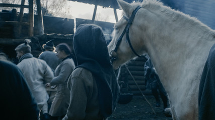 Medieval Reenactment. Life in the Yard of the Wooden Fortress, People with Horses. Assassin. - obrazy, fototapety, plakaty