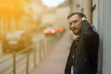 Portrait of a handsome young hipster man while listening to music on his headphones in an urban environment.