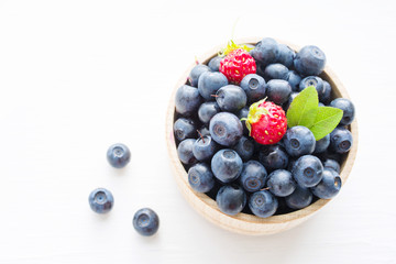 Fresh blueberries in a wooden cup on a light surface. Closeup, top view.
