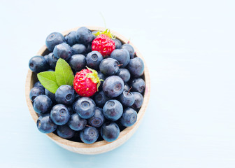 Fresh blueberries in a wooden cup on a light surface. Closeup, top view.