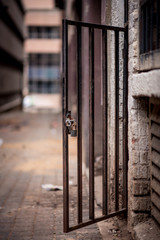 A metal doorway with padlock stands open in a dirty alleyway. Johannesburg inner city