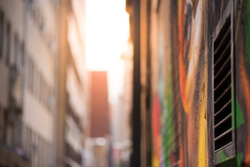 Fototapeta premium Zdjęcie abstrakcyjne stylu patrząc w dół alejki wyłożonej graffiti w kierunku słońca. Centrum Johannesburga