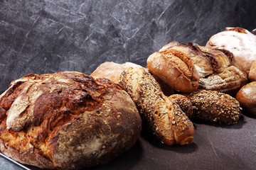 Different kinds of bread and bread rolls on board from above. Kitchen or bakery