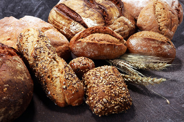 Fototapety  Different kinds of bread and bread rolls on board from above. Kitchen or bakery