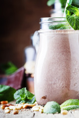 Chocolate-mint creamy smoothies in bottles on an old wooden background, selective focus