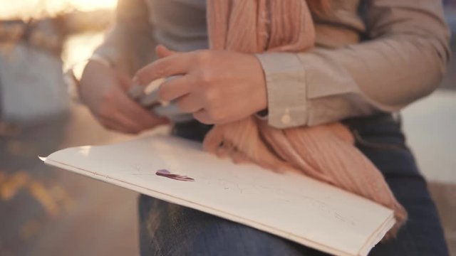 close shot on artist hand, woman holds colorful pens and draws on special paper an abstract drawing, a woman is on the planner for inspiration
