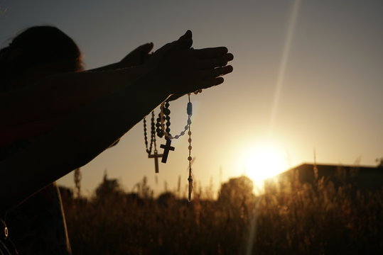 children pray on rosaries at sunset
