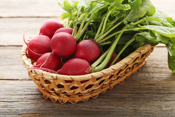 Red radishes in basket on grey wooden table