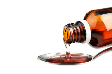 Bottle pouring medical syrup in spoon on white background