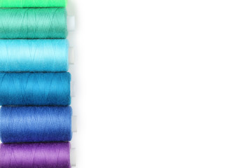 Colourful thread spools on white background