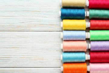 Colourful thread spools on white wooden table