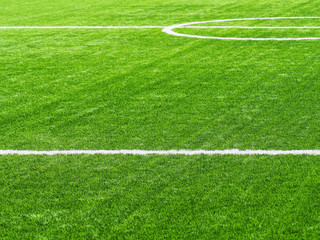Green synthetic grass on sport ground with white lines. White stripe on the green soccer field from side view. Artificial turf on football field