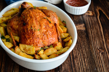 Chicken baked with potatoes in a white bowl.