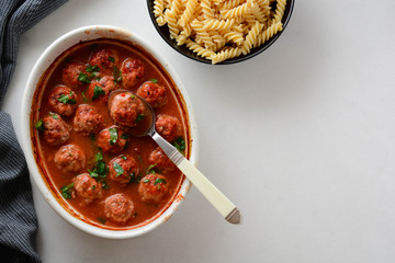 Pasta with meatballs and tomato sauce on table.