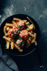 Pasta with meatballs and tomato sauce on table.
