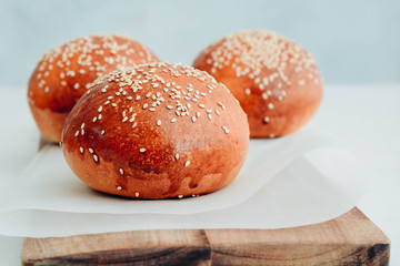 Round bun, sesame bun, bread rolls. Tasty burger bread with sesame on wooden. Freshly baked hamburger buns.