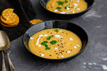 Carrot, ginger, turmeric soup in a bowl on marble background. Empty space for text.
